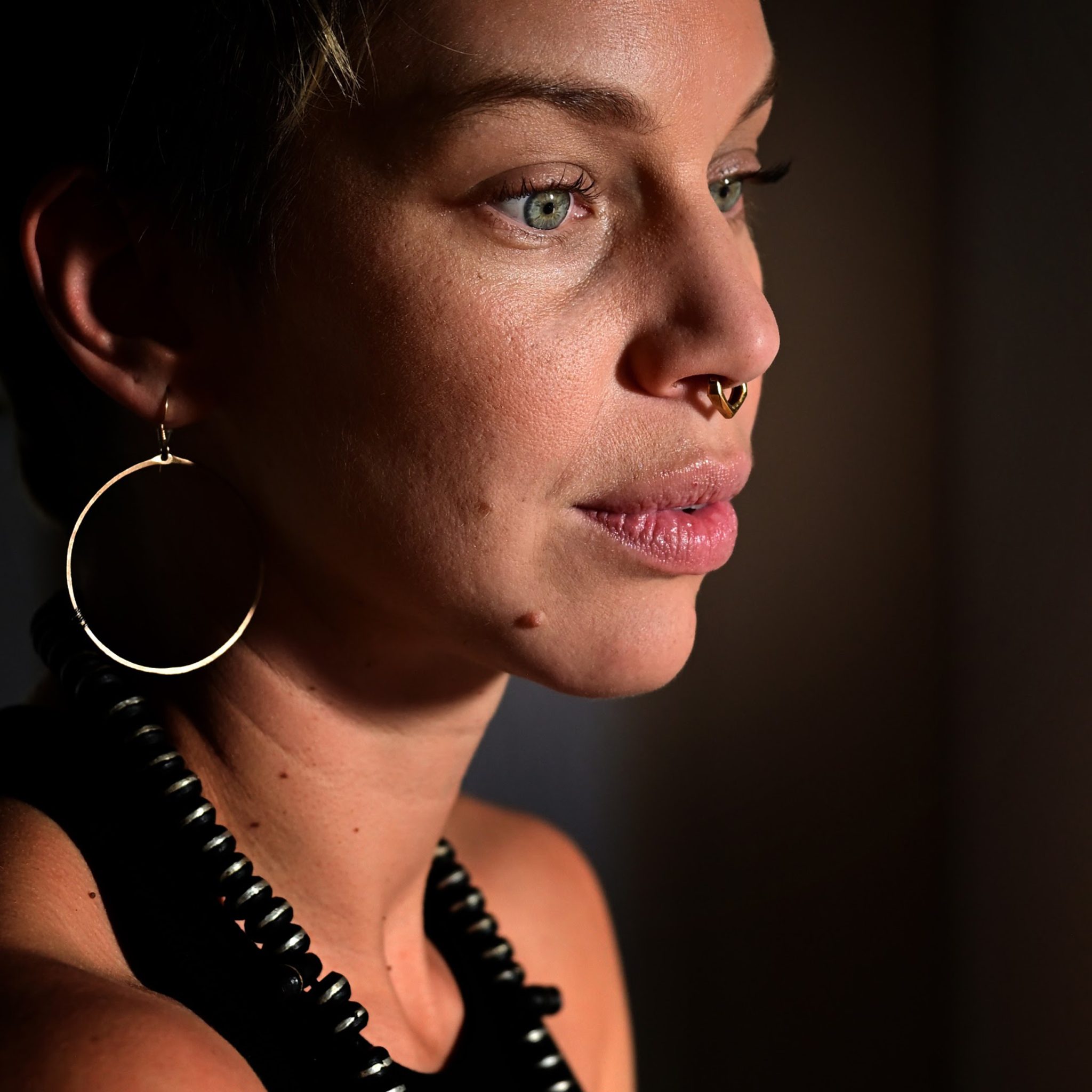 Close portrait of a woman in profile against a dark background.