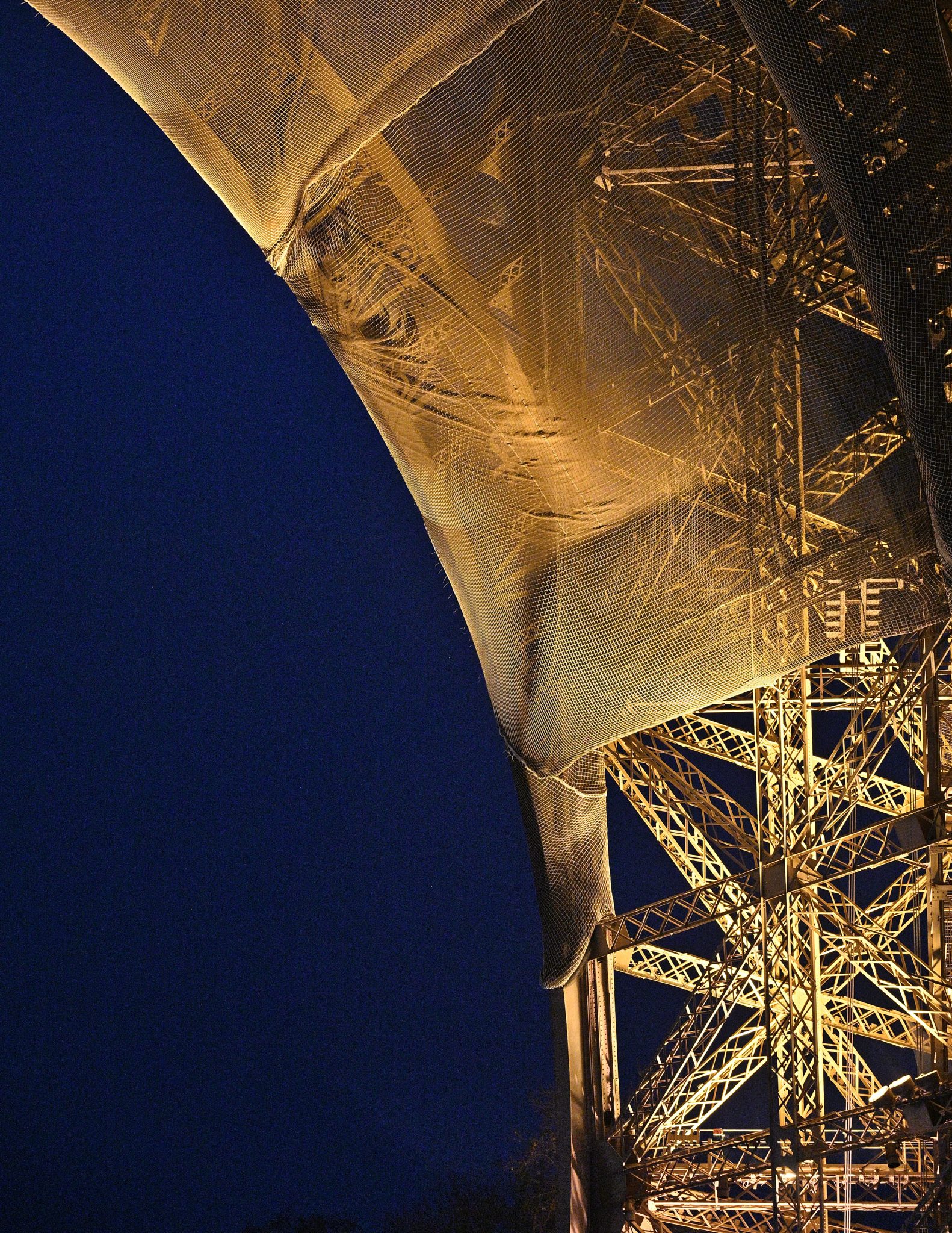 Abstract architectural structure lit in warm gold against a deep blue background.