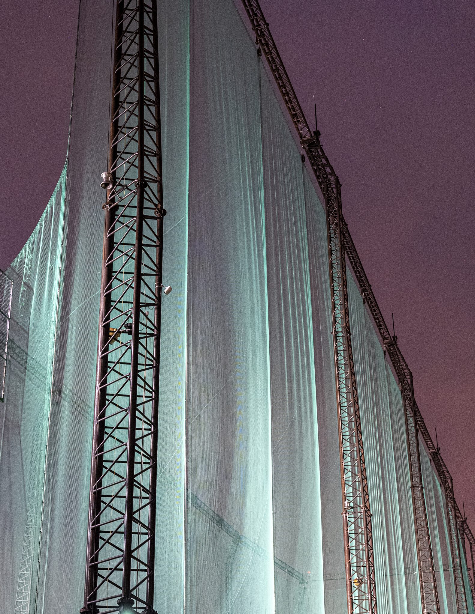 Vertical architectural structure with pale illuminated panels and dark metal lines.