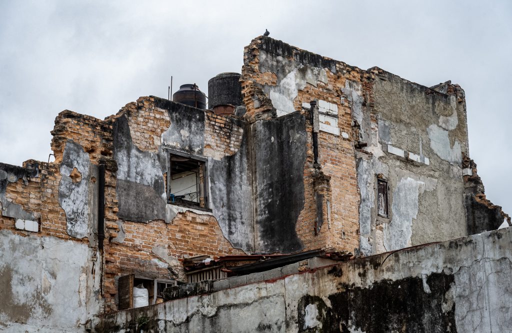 Weathered brick and plaster walls of a partially ruined building.