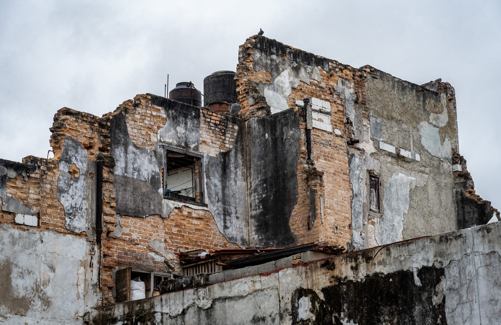 Weathered brick and plaster walls of a partially ruined building.