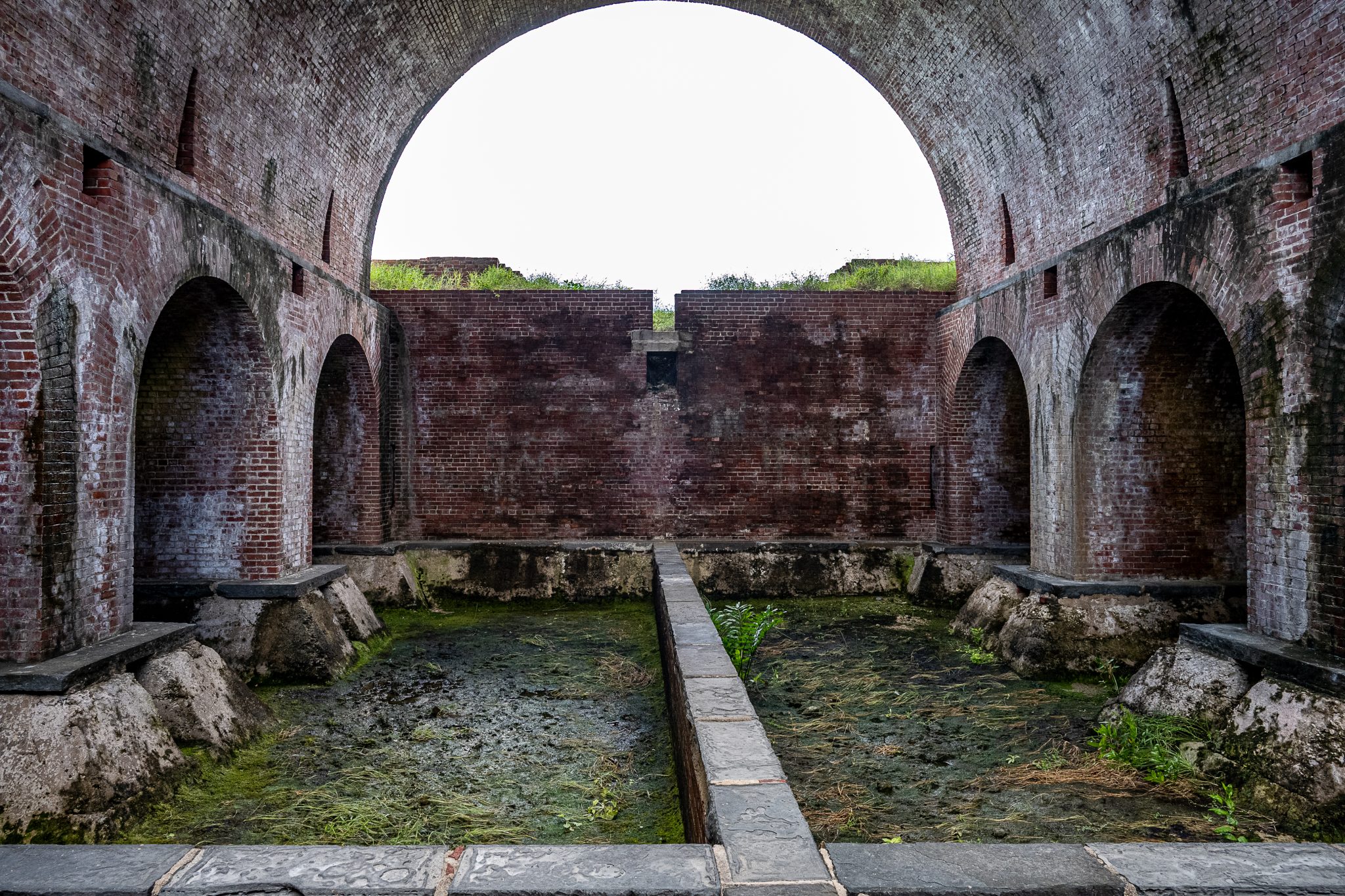 Stone arch opening onto a partially ruined courtyard.